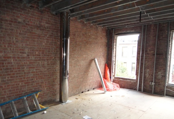 exposed chimney pipe on exposed brick wall